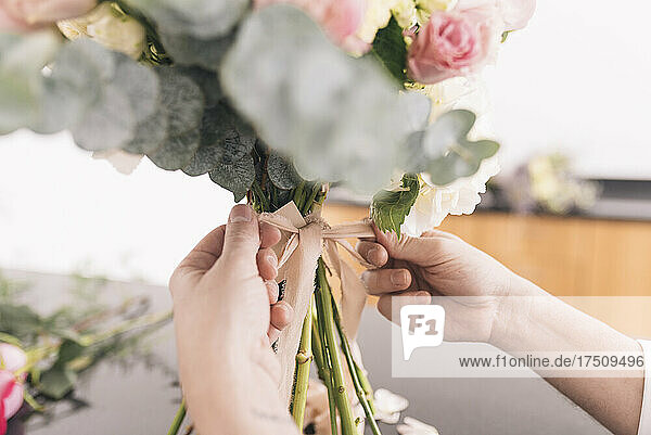 Hands of male florist preparing bouquet