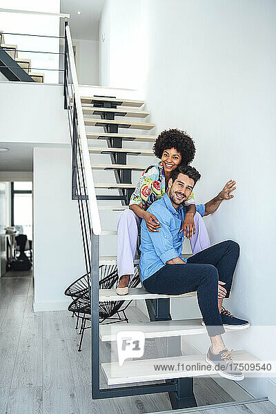 Happy couple sitting on floating stairs in modern penthouse