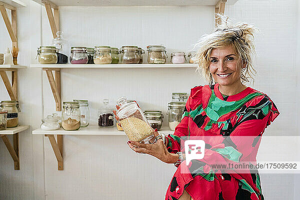 Smiling female cook holding spice container while sitting in cooking class