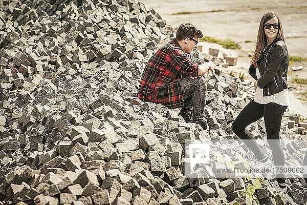 Teenage boy and girl on rubble in an old run down industrial area