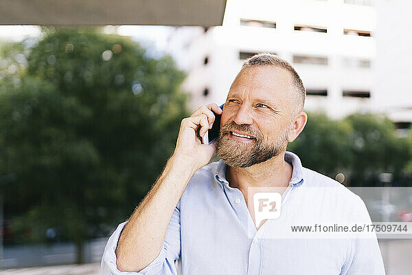 Close-up of smiling male entrepreneur talking on mobile phone