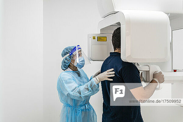 Female nurse helping male patient in scanning at hospital