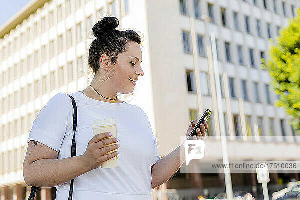 Kurvige junge Frau benutzt Mobiltelefon in der Stadt