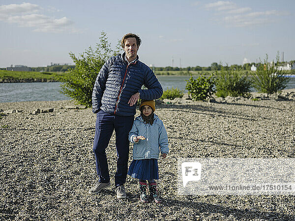 Father with daughter standing on land against Rhine river during sunny day