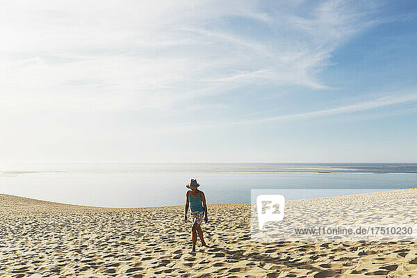 Woman walking on sand dunes at beach against sky  Dune of Pilat  Nouvelle-Aquitaine  France