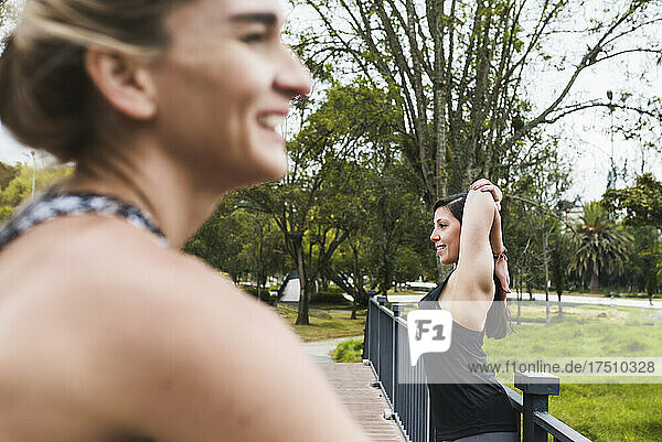 Smiling female friends looking away while exercising in park