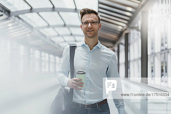 Businessman with coffee walking in city