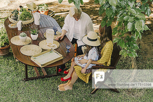 Multi-generation family enjoying picnic at table in yard