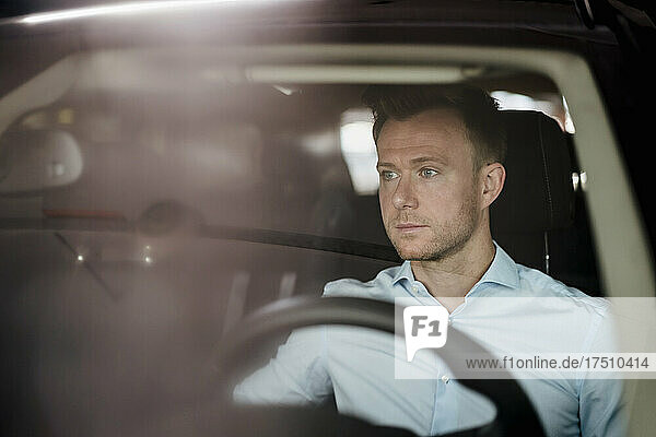Serious male entrepreneur looking away while sitting in car