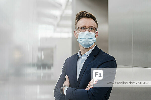 Businessman with arms crossed wearing face mask in city