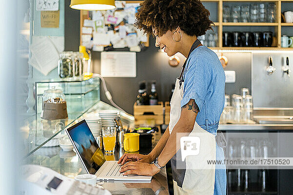 Besitzerin benutzt Laptop am Tresen im Café