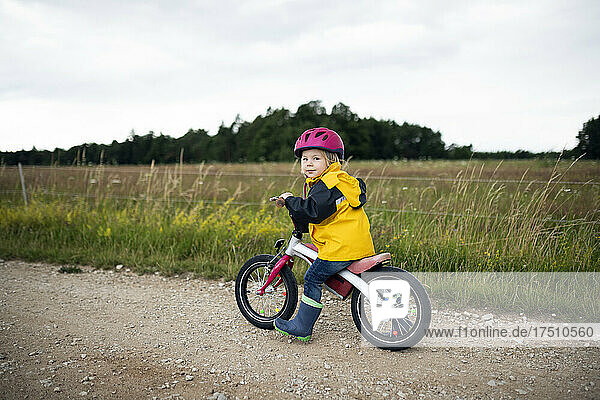 Toddler girl with pink cycling helmet on balance bicycle