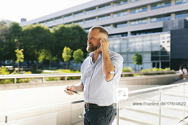 Businessman listening music through earphones at balcony