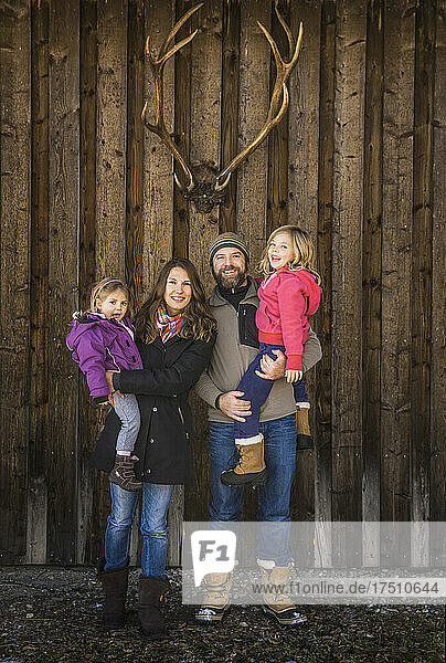 Portrait of a smiling family in front of a cabin with deer antlers
