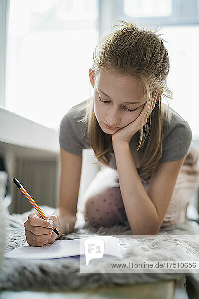 Girl learning at home  writing in exercise book