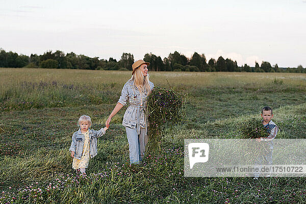Lächelnde Mutter mit zwei Kindern  die auf dem Feld spazieren