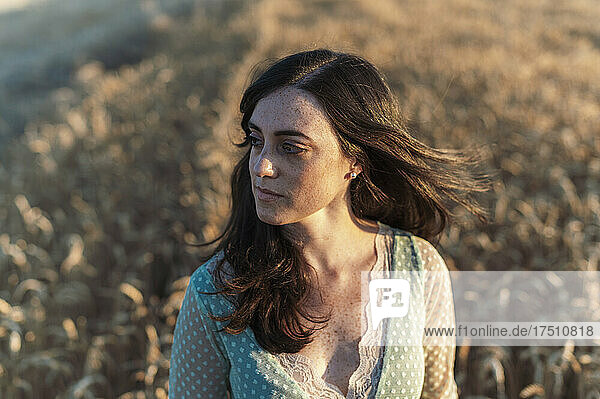 Close-up of thoughtful beautiful woman looking away in farm during sunset