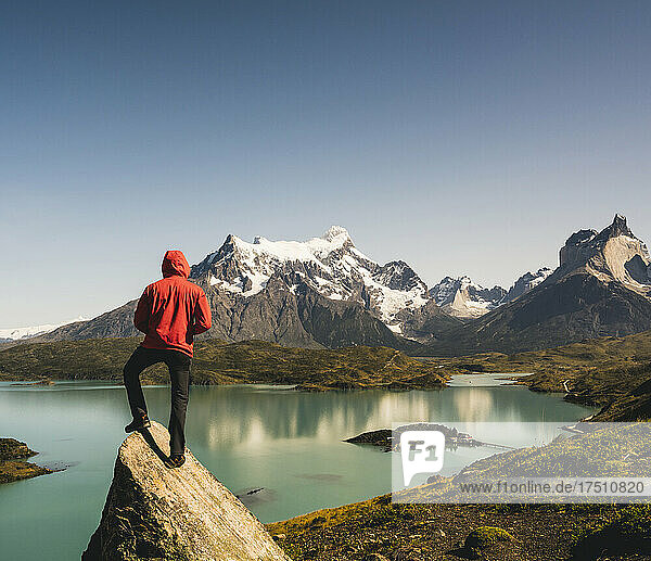 Man in hooded jacket standing on rock at Lake Pehoe in Torres Del Paine National Park  Chile Patagonia  South America