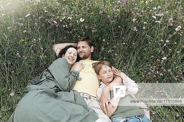 Smiling parents with son lying on land amidst flowers
