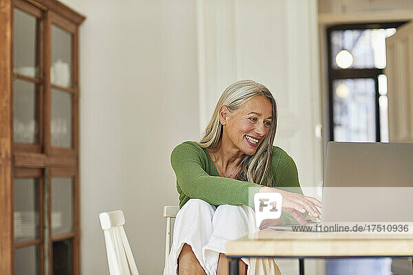 Lächelnde Geschäftsfrau  die zu Hause Laptop benutzt