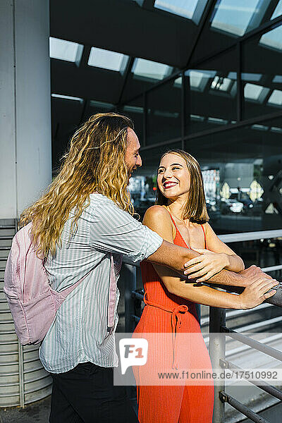 Smiling couple looking face to face while standing at train station