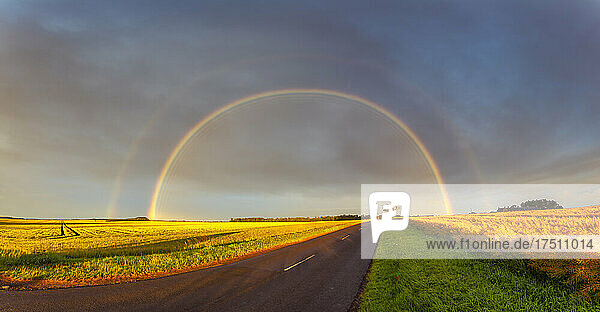 Double rainbow arching over empty countryside highway