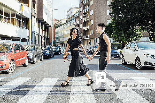 Smiling lesbian couple crossing road in city