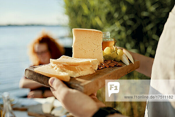 Man serving cheese platter for friends at a lake