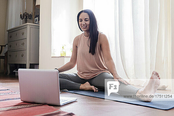 Lächelnde reife Frau vor dem Laptop zu Hause