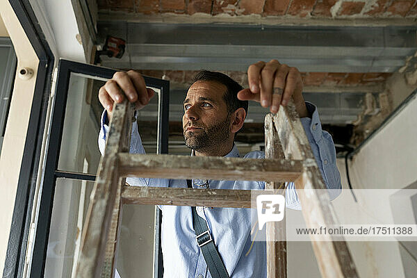 Thoughtful architect at step ladder in a house under construction