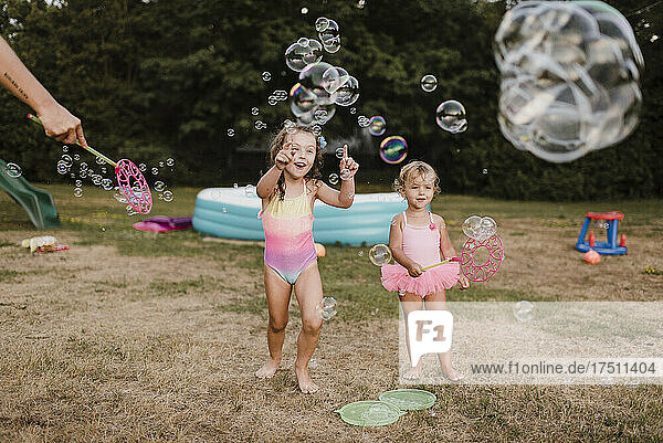 Two happy girls playing with soap bubbles in garden
