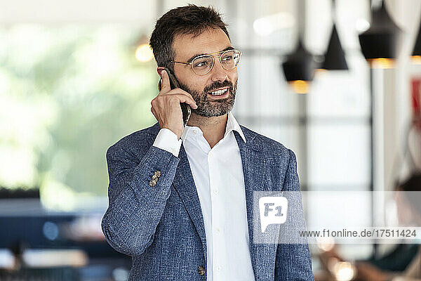 Businessman talking on mobile phone while standing at cafe