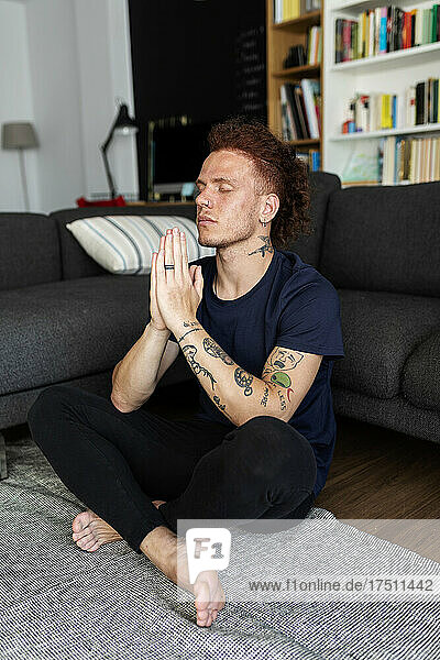 Man praying while sitting on floor at home