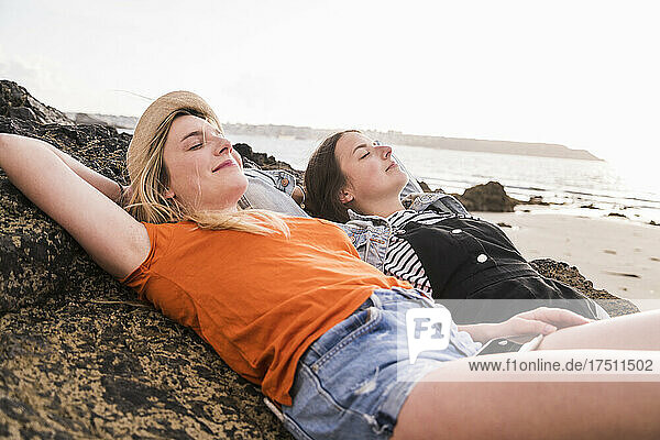 Two girlfriends relaxing on rocky beach