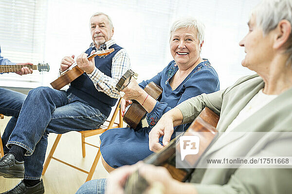 Seniors in retirement home attending guitar class  making music