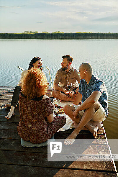 Friends having picnic on jetty at a lake