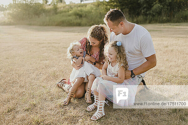 Happy parents with two daughters on a meadow