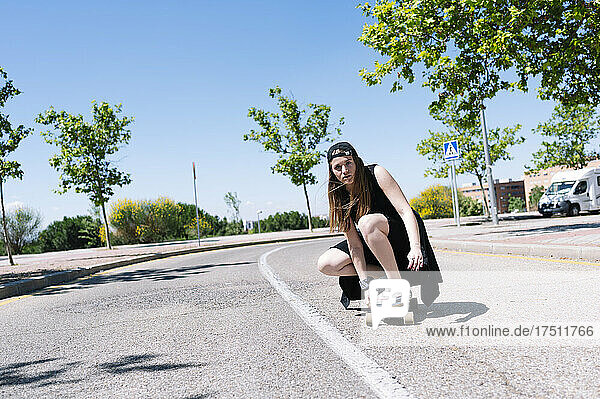 Young woman skateboarding along meridian srtip of empty road