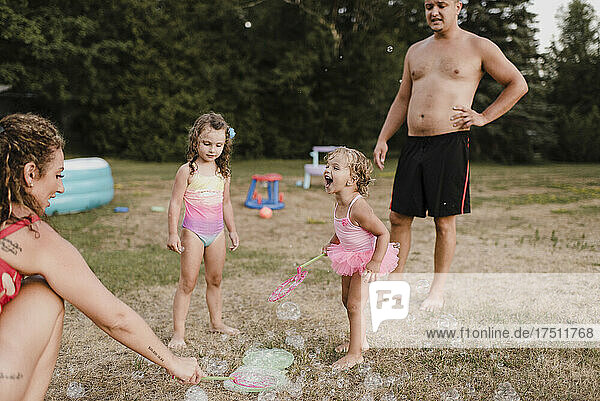 Glückliche Familie spielt mit Seifenblasen im Garten