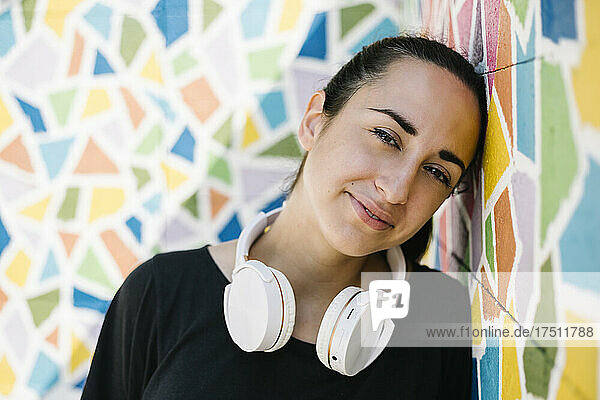 Portrait of woman with white headphone in front of colorful wall