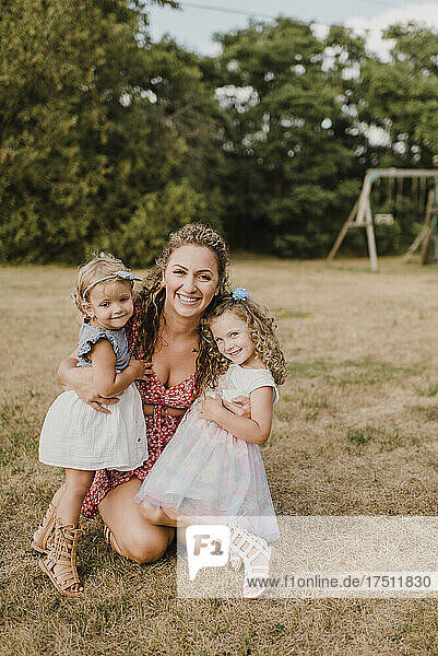 Happy mother hugging daughters on a meadow