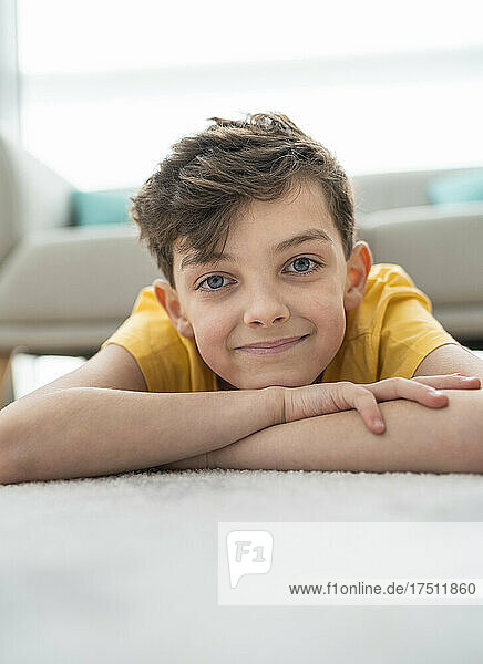 Nahaufnahme eines lächelnden Jungen  der auf dem Teppich im Wohnzimmer liegt