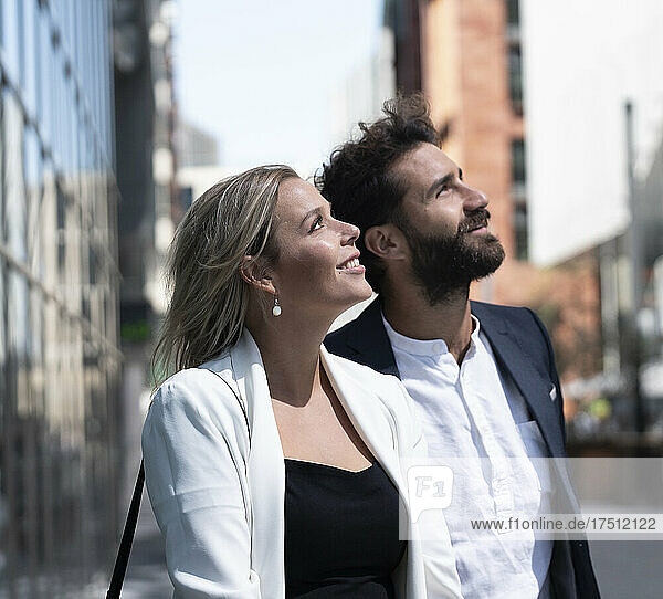 Businessman and businesswoman in business district in the city looking up