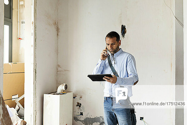 Architect with tablet on the phone in a house under construction