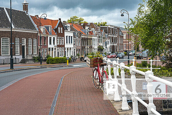 Netherlands  North Holland  Haarlem  Bicycle parked along railing of canal bridge with houses along Hooimarkt street in background