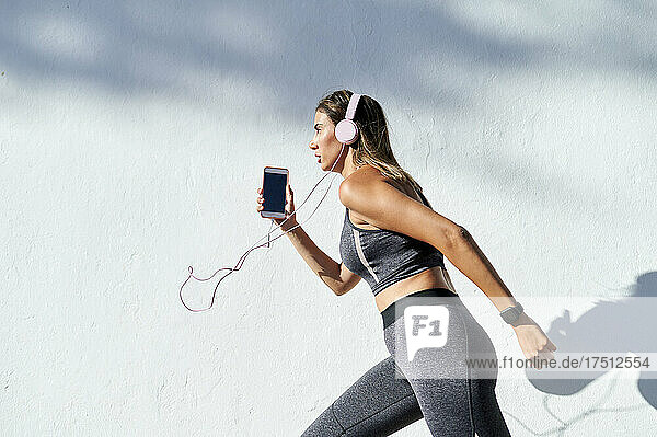 Woman listening to music while running in city