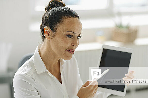 Close-up of female entrepreneur holding digital tablet looking away in home office