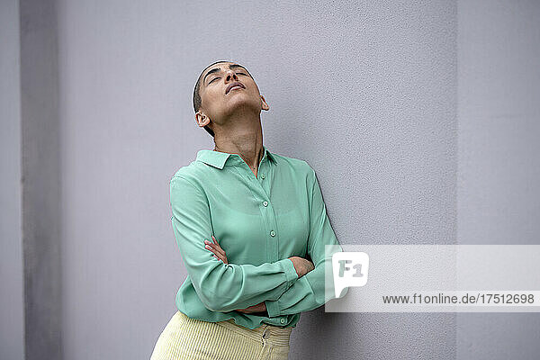Woman with closed eyes leaning against wall