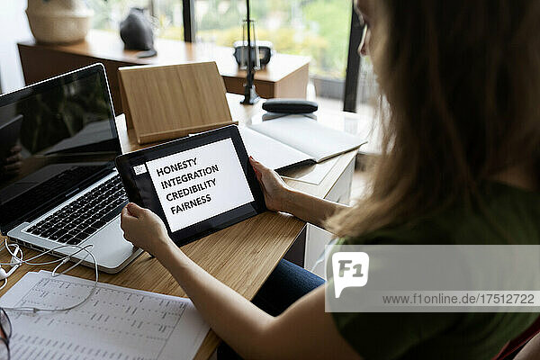 Close-up of businesswoman using digital tablet on desk in home office