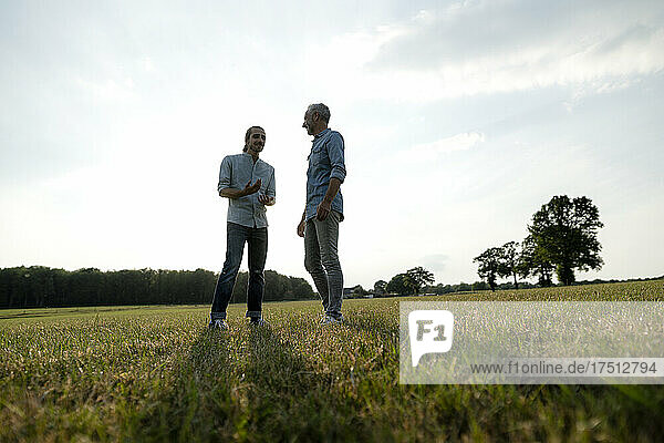 Father and adult son standing on a meadow in the countryside